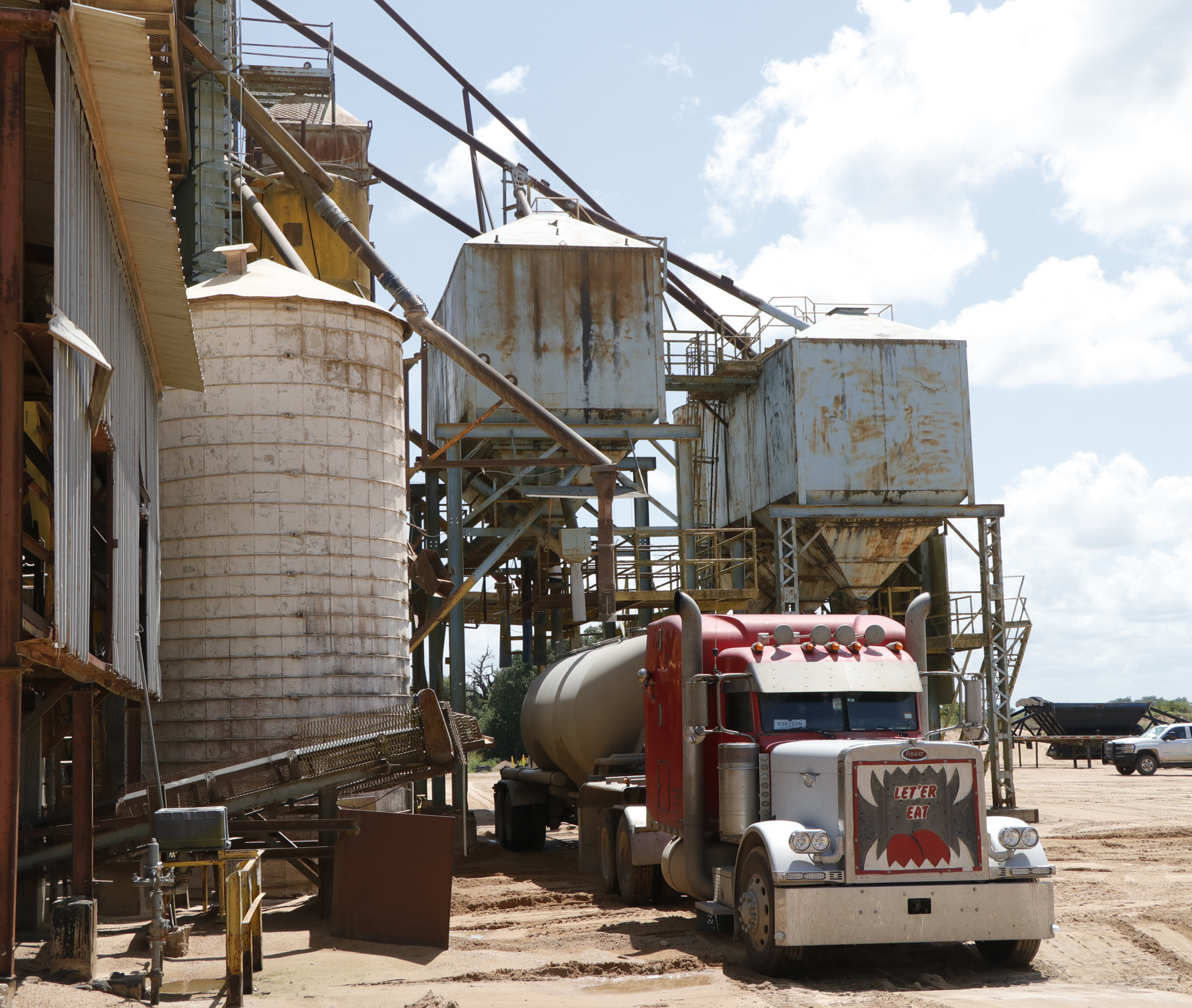 Truck parked at industrial facility under sky.